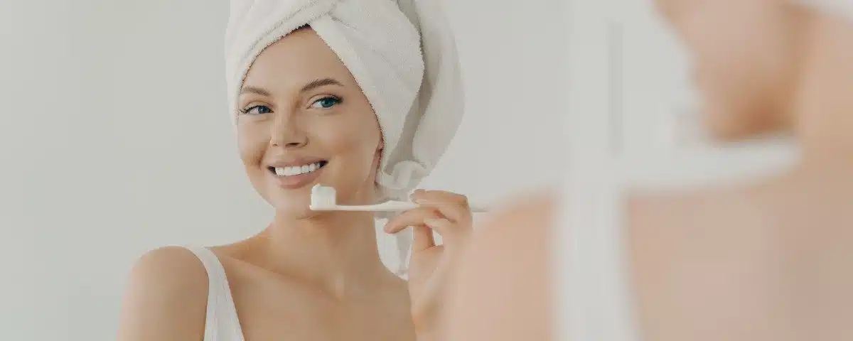 une femme qui se brosse les dents devant le mirroir