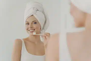une femme qui se brosse les dents devant le mirroir